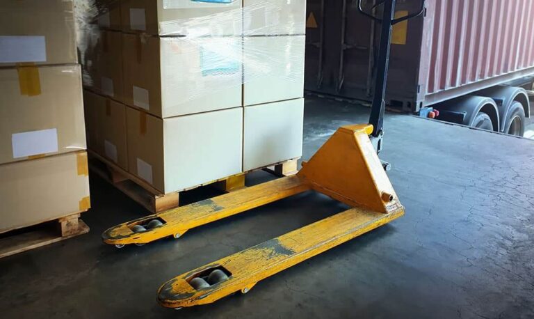 A pallet jack next to a loaded pallet.